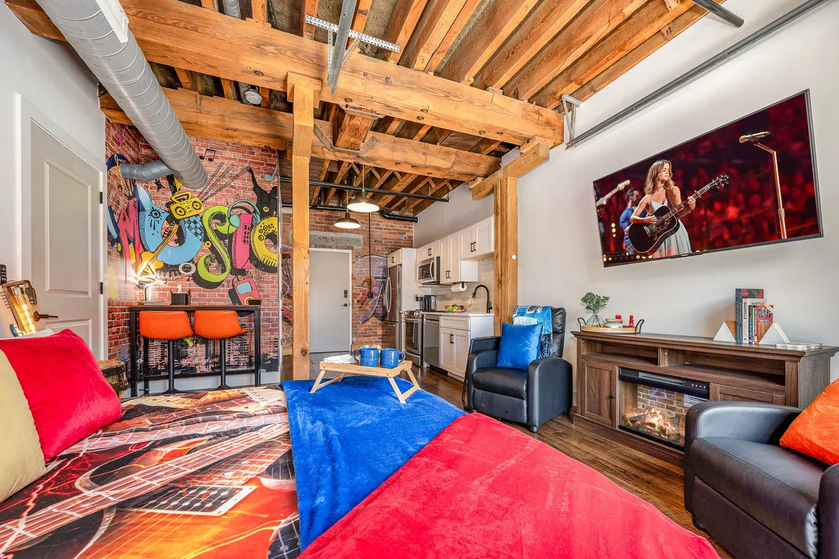 The hero image showcases a vibrant, music-inspired studio space with a striking colorful mural, a modern kitchen, plush seating area, and a TV displaying live music performances. The layout is open and inviting, perfect for both relaxing and entertaining, with creative touches that reflect Nashville's artistic spirit.
