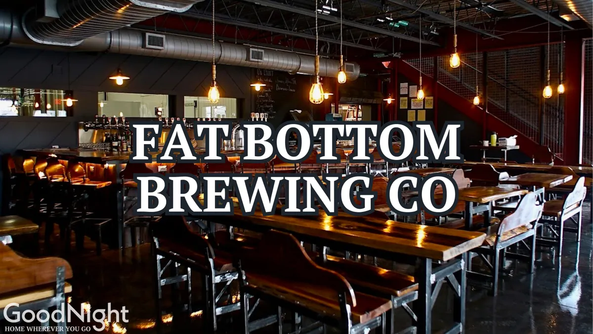 This image features a stylish, atmospheric bar interior with long wooden tables, industrial light fixtures, a prominent bar area, and large windows that allow warm light to stream in. The setup is perfect for socializing, live music, and craft cocktails, capturing the essence of a lively speakeasy environment.